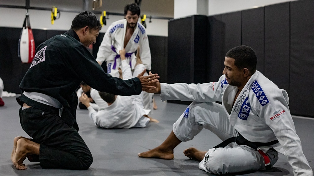 BJJ World Champion Bismark Gomez shaking hands with a student after a good roll.